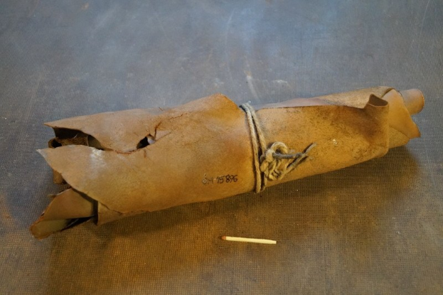 Ein brauner Papiertütenbeutel, der wie eine Granate geformt ist und mit einem Seil zusammengebunden ist, liegt auf einem Tisch neben einer Zigarette.