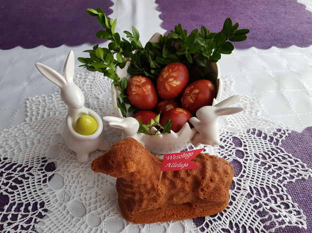 Ein Tisch mit einer Decke darauf hält eine Schüssel mit bunten Ostereiern und Osterhasenfiguren darauf.