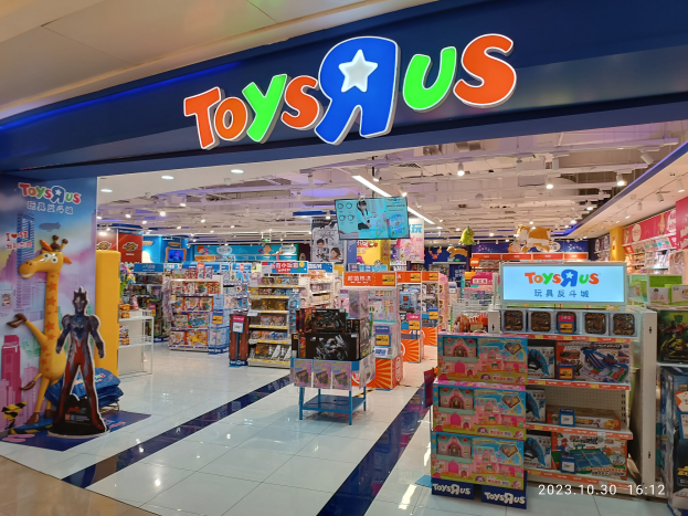 Ein Toys R Us Geschäft im Einkaufszentrum, das Regale mit Spielzeug und Artikeln zeigt, mit Deckenbeleuchtung und einem sichtbaren Namensschild.