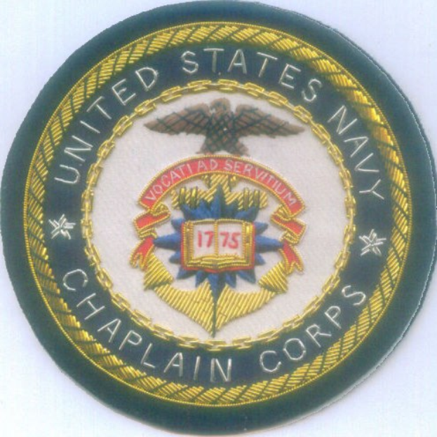 Ein rundes Abzeichen mit einem blauen Hintergrund und weißer Umrandung, auf dem der weiße Text 'United States Navy Chaplain Corps' in der Mitte steht.