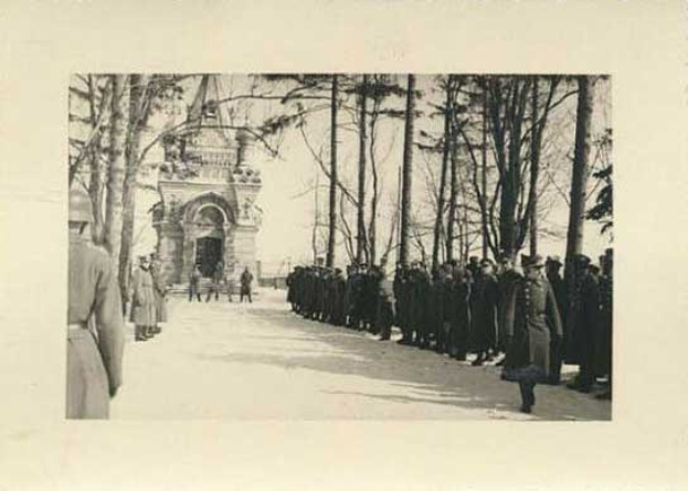 Schwarz-weißes Foto einer Trauerprozession mit Menschen vor einem Gebäude mit einem Tor, Bäumen an der Straße und dem Text "Trauerprozession für die Opfer der Berliner Mauer" unten.