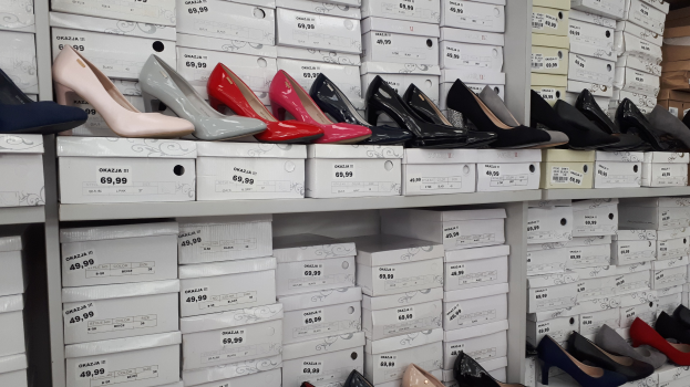 Ein Regal voller verschiedener Schuhe in Kartons, jeder mit einem Preisschild, und Kartons aus Pappe auf der rechten Seite.