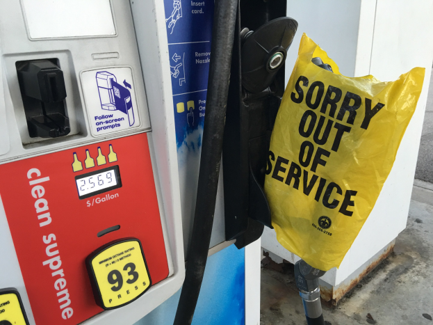 Tankstelle mit einem "Sorry Out of Service" Schild und einer gelben Abdeckung, die als Kraftstoffspender gekennzeichnet ist.