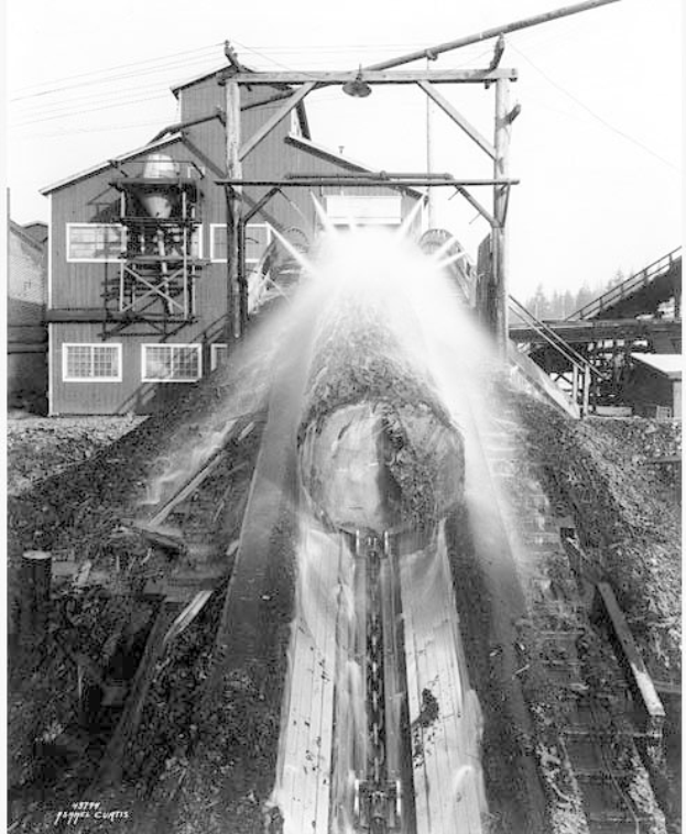 Schwarzes und weißes Foto eines Zuges, der auf Schienen mit einem mehrfenstrigen Gebäude, Strommasten mit Drähten, Bäumen und Himmel im Hintergrund fährt, beschriftet mit "Curtis Coal Mine, Washington, D.C." unten.