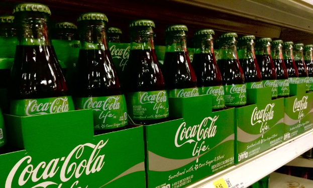 Gläser sind in grünen Kartons mit 'Coca-Cola Life' darauf gestellt.
