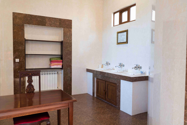 Badezimmer mit zwei Waschbecken, Schränken, einem Tisch und Stühlen, einem Foto auf der Wand, einem Fenster und einem Handtuchhalter.