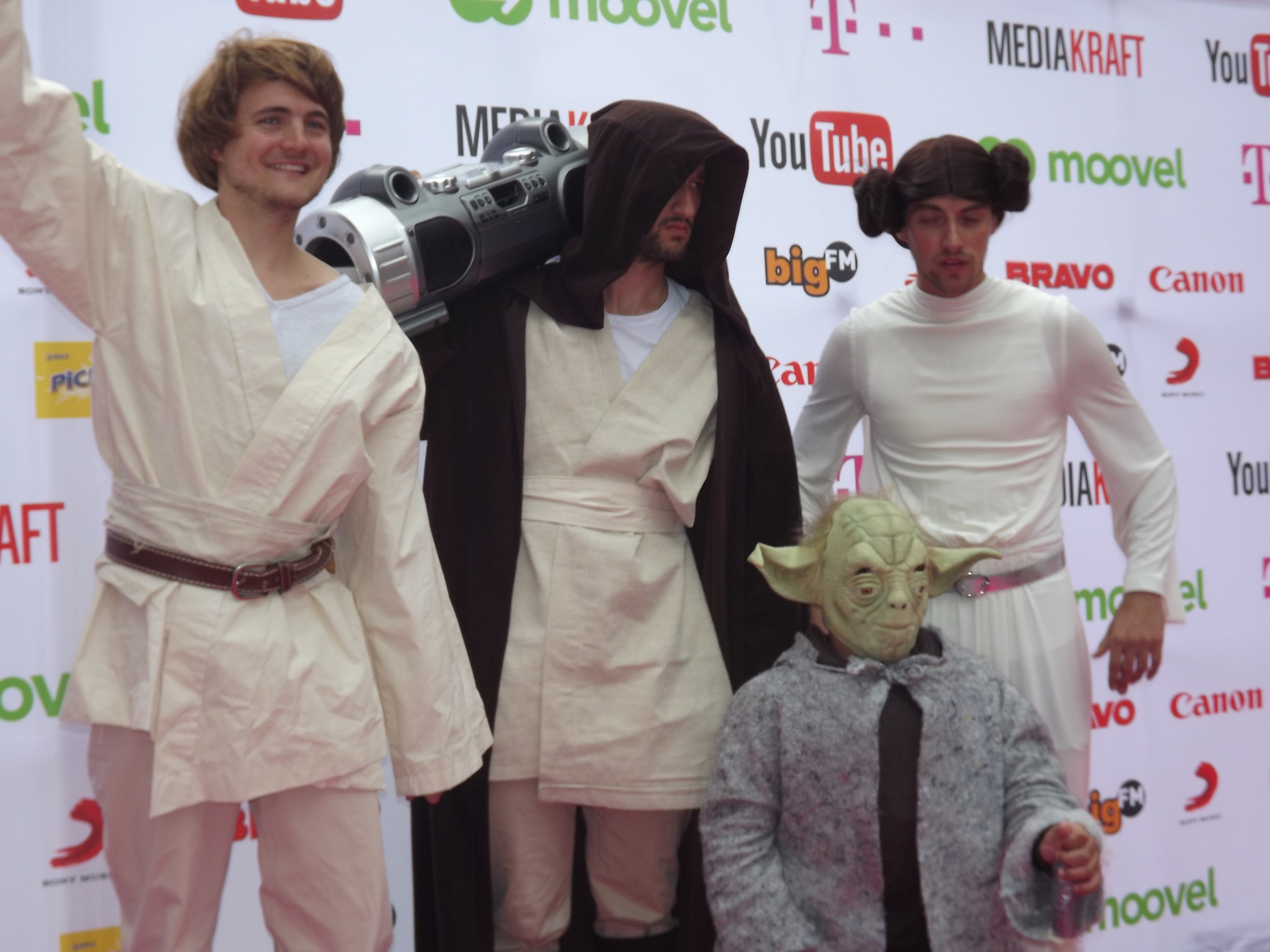 Eine Gruppe von Menschen in Star-Wars-Kostümen posiert auf einem roten Teppich mit einem Banner im Hintergrund.