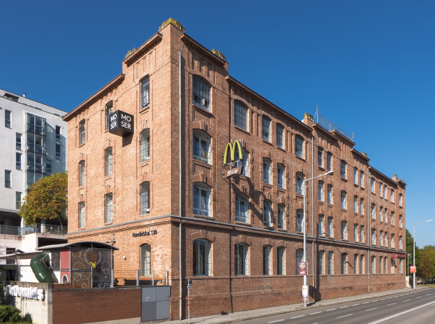 Ein großes McDonald's-Restaurantgebäude aus Backstein an einer Straßenecke in Berlin, Deutschland, mit umgebender Straßeninfrastruktur und Vegetation.