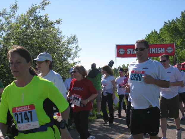 Eine Gruppe von Kindern beim Laufen in einem Marathon, mit einem roten Banner und Bäumen im Hintergrund.