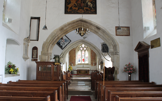 Eine Kirche von innen mit Blumenvasen, Bänken, Fotorahmen und Lichtern.