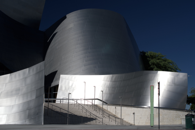 Die ARTIST Concert Hall in Los Angeles, ein großes Gebäude mit einer Treppe zum Eingang, umgeben von Straßenmasten, Bäumen und einem Mülleimer, unter einem bewölkten Himmel.