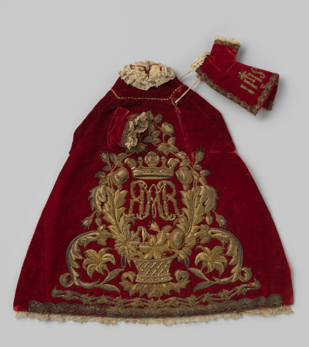 Ein roter Samtmantel mit goldener Stickerei und einer Krone, der aufwändige Designs zeigt, vor einem weißen Hintergrund.