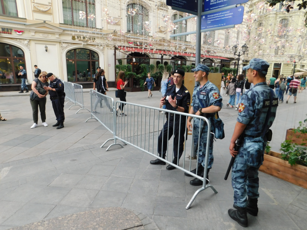 Polizeibeamte in Uniform hinter Barrieren vor einer Menge, einige mit Waffen, mit Gebäuden, Bäumen und Laternen im Hintergrund während einer Anti-Terror-Operation in Wien, Österreich.