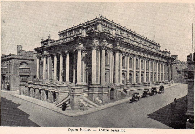 Ein altes Schwarz-Weiß-Foto des Teatro Massimo Opernhauses in Rom, Italien, mit einem großen Gebäude mit Säulen, Treppen und Bögen, sowie einigen Menschen und Karren auf der Straße davor und Text am unteren Rand des Bildes.