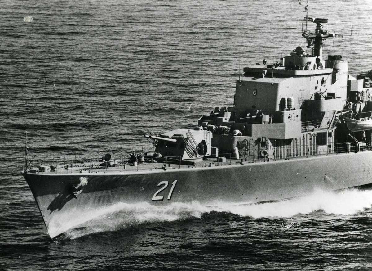 Ein Schwarz-Weiß-Foto eines großen Lenkwaffen-Fregatters mit einer sichtbaren Identifikationsnummer, das auf dem Wasser fährt.