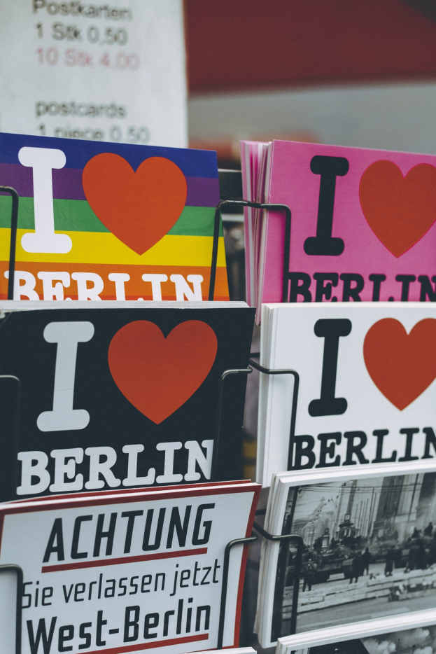Ein Gestell, auf dem verschiedene Bücher und Plakate mit der Aufschrift "Ich liebe Berlin" in einer sanft unscharfen, träumerischen Umgebung stehen.