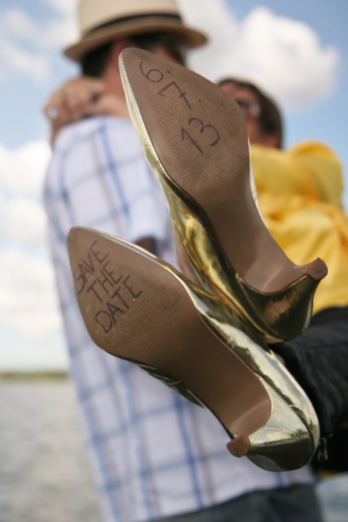 Frauen-Absätze mit Text darauf, mit einer Person, die die Beine einer Frau hinter den Absätzen hält.