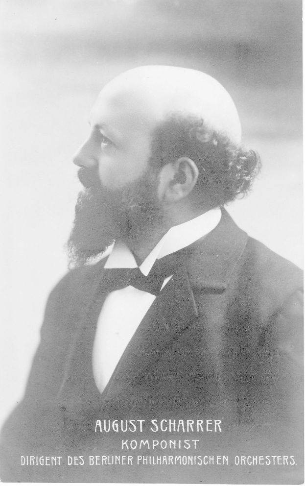 Ein Schwarz-Weiß-Foto von August Scharrer, einem deutschen Komponisten, der einen Blazer und eine Fliege trägt, mit Text am unteren Bildrand.
