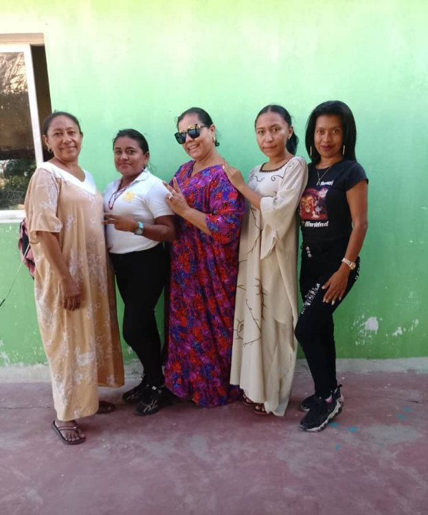 Gruppe von Frauen vor einer grünen Wand mit einem Fenster auf der linken Seite bei einer Internationalen Frauentagsveranstaltung.