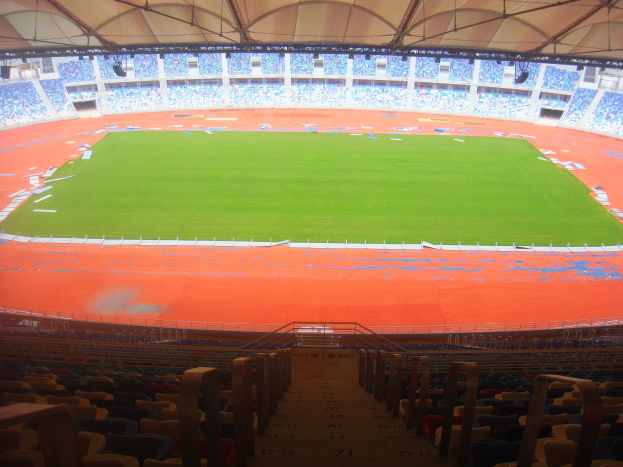 Ein großes Stadion mit vielen Zuschauern, das über Sitzreihen, Geländer, Treppen und ein Dach verfügt, mit dem Spielfeld in der Mitte sichtbar.