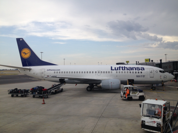 Lufthansa Airbus A320-200 am Frankfurter Flughafen mit Bodenbetriebsfahrzeugen, Absperrkegeln und Beschilderung im Hintergrund.