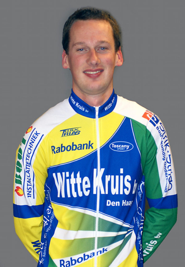 Ein Sportler posiert für ein Foto, trägt ein Hemd mit verschiedenen Sponsorennamen.