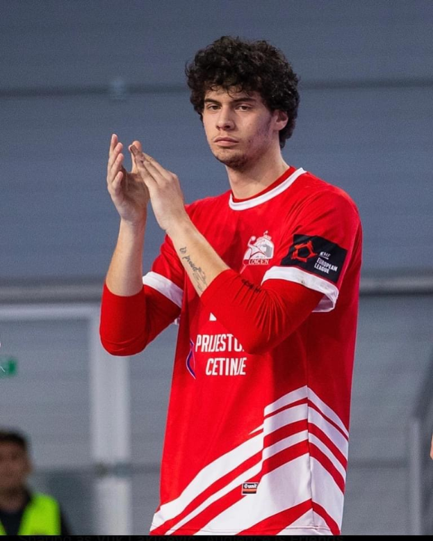 Ein Mann in rot-weißem T-Shirt klatscht in der Vordergrund, mit einer anderen Person und einer Wand im Hintergrund, Text unten lautet "Copenhagen Futsal Club - Foto 1".