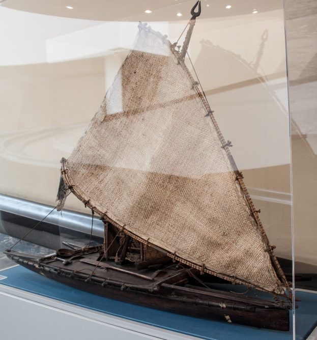Ein Modellsegelboot mit geschwellten Segeln in einer Glasvitrine gegen eine Wand mit Deckenbeleuchtung.