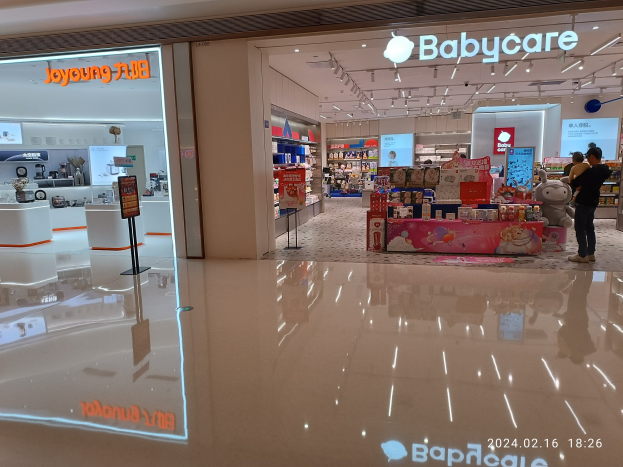 Babycare-Laden inmitten eines Einkaufszentrums umgeben von Spielzeug, Regalen, Schildern, einem Bildschirm und Deckenleuchten, gelegen im Mall of Asia.