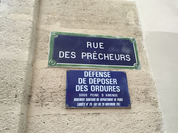 Zwei blaue und weiße Straßenschilder an der Seite eines Gebäudes angebracht.