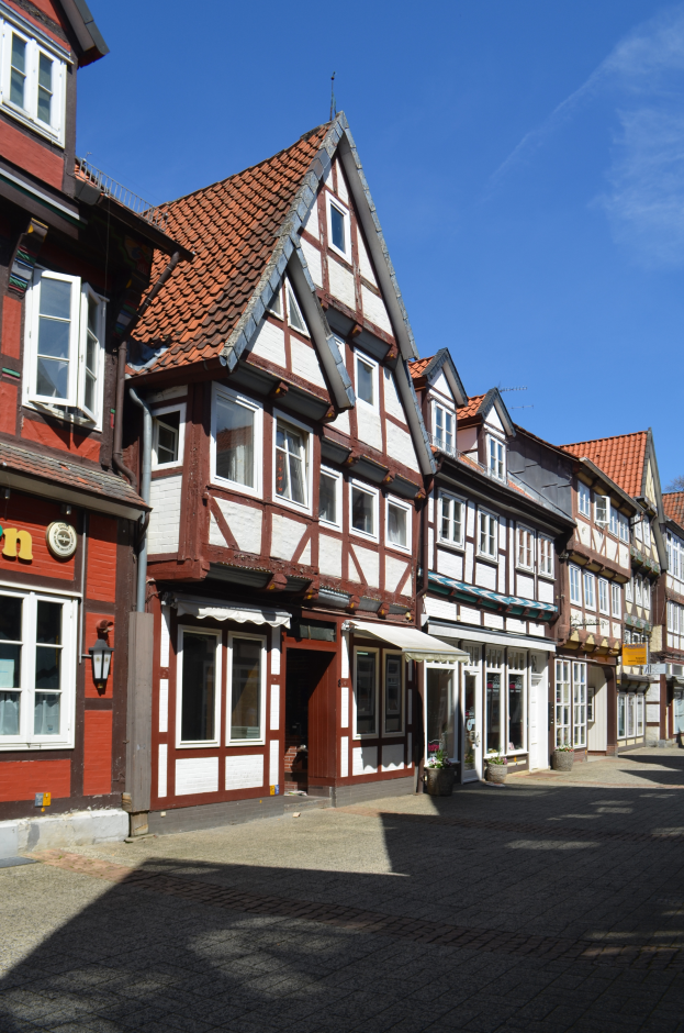 Ein Kopfsteinpflasterweg in der Altstadt von Heidelberg, mit Gebäuden im Vordergrund, einem klaren blauen Himmel im Hintergrund und einer Lampe, die die Straße auf der linken Seite beleuchtet.