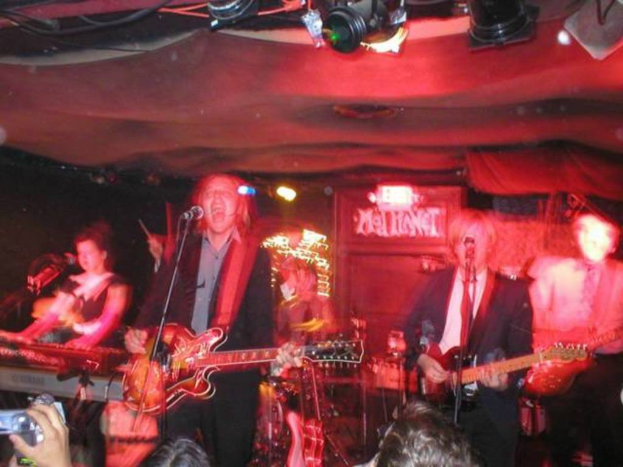 Eine Gruppe von Menschen singt auf der Bühne mit Gitarren, während andere vorne Videos aufnehmen.