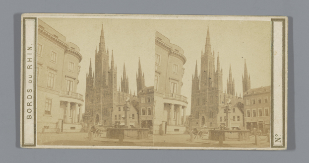 Altes Schwarz-Weiß-Foto einer Stadtstraße mit Gebäuden, Straßenlaternen, Pferdefuhrwerken, Menschen und Bäumen entlang der Straße.