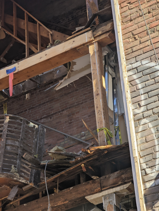 Ein teilweise abgerissener Bau mit verstreuten Holzplanken und Schutt, mit zerbrochenen Fenstern und Türen.