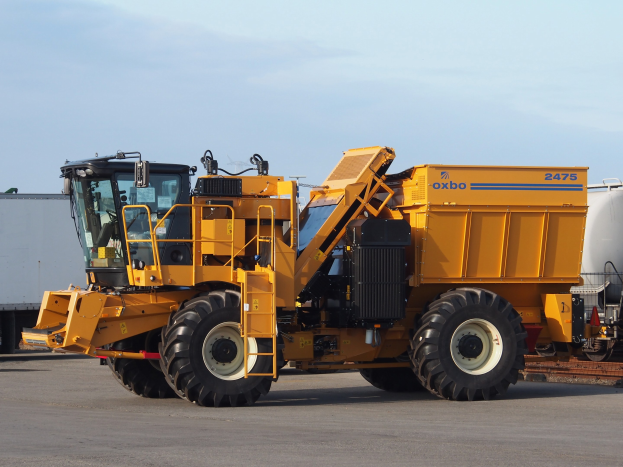 Ein großer gelber Radlader vor einem weißen Container auf einer Straße mit einem klaren blauen Himmel im Hintergrund.